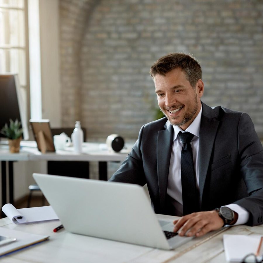 happy-male-entrepreneur-reading-email-laptop-while-working-office_637285-6756